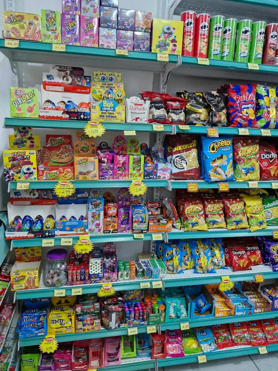Prateleiras com chocolates, balas, pirulitos e salgadinhos.