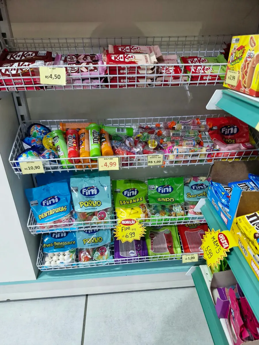 Expositor com chocolates, balas de gelatina e doces embalados.